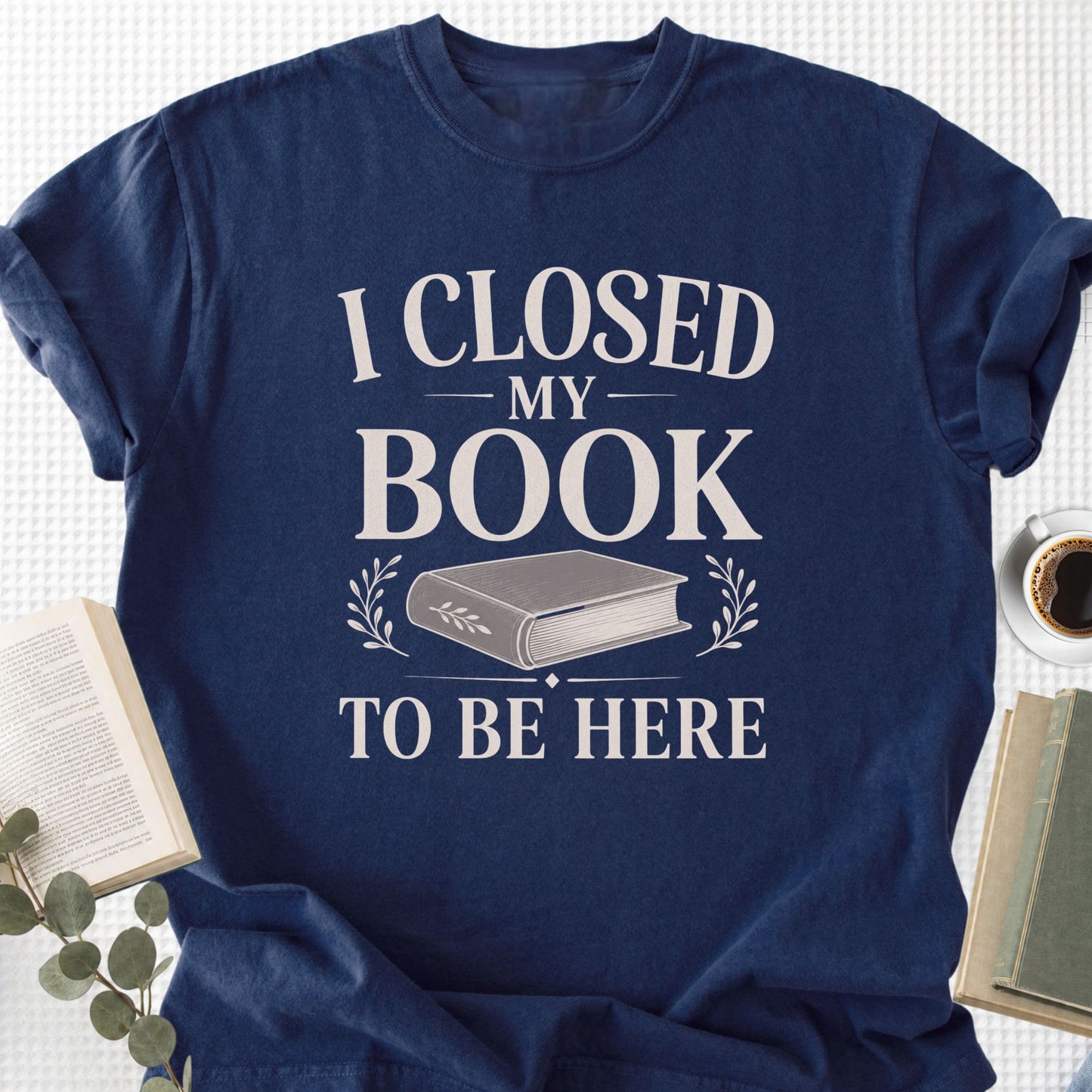 Navy blue t-shirt with 'I Closed My Book To Be Here' text on a white background